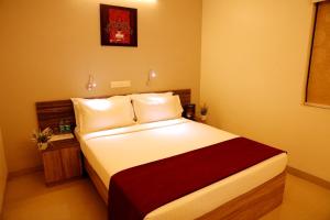 a bedroom with a bed with white sheets and red blanket at Downtown Business Hotel in Singapperumālkovil +31 photos