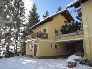 una casa amarilla con nieve delante en Schangri-la, en Ramsau am Dachstein