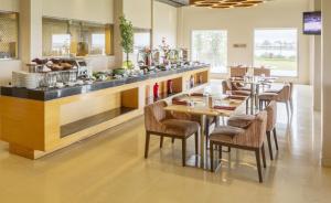 a restaurant with a counter with tables and chairs at Hotel Naveen Lakeside in Hubli