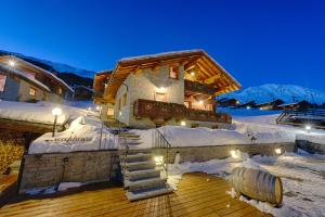 a log cabin in the snow at night at Residence Lo Peyo in Champoluc