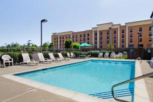 a swimming pool with chairs and a building in the background at Wingate by Wyndham Vineland in Vineland