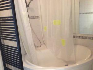 La salle de bains est pourvue d'une douche avec rideau de douche blanc. dans l'établissement James D, au Coq