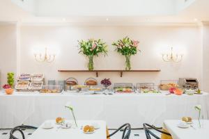 een kamer met tafels met borden met eten en bloemen bij Raeli Hotel Luce in Rome