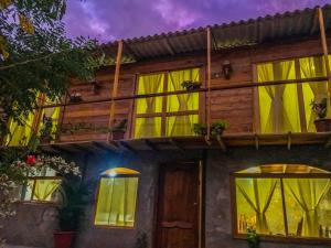 Cette maison dispose de fenêtres jaunes et d'un balcon. dans l'établissement Buganvilla Guest House, à Ballenita