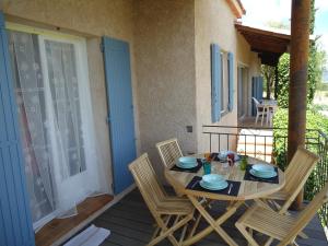 een houten tafel en stoelen op een veranda met een tafel en stoelen bij le petit coin de Noah in Châteauneuf-Val-Saint-Donat