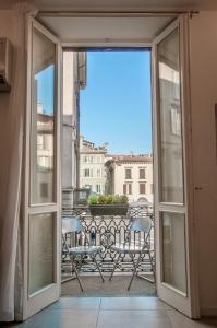 Une porte ouverte s'ouvre sur un balcon avec une table et des chaises. dans l'établissement FASHION HOUSE ELVIRA 1, à Bergame