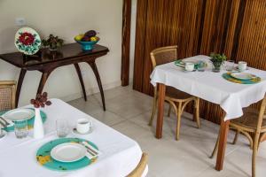 - une salle à manger avec 2 tables, des assiettes et des bols de fruits dans l'établissement Casa Clara Paraty, à Parati