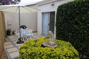 a patio with an umbrella and a statue in a bush at Palm Cottage in Durban