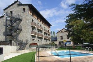 a building with a swimming pool in front of it at Roca Nevada Resort in Villanúa