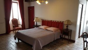 a bedroom with a bed and two chairs and windows at La Closeraie in Champagné-les-Marais