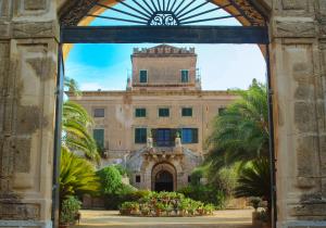 une entrée à un bâtiment avec une tour d'horloge dans l'établissement Ville Mirto, à Santa Flavia