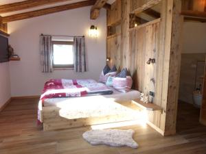 sypialnia z łóżkiem z drewnianą ścianą w obiekcie Sonnberg Apartment w mieście Niedernsill