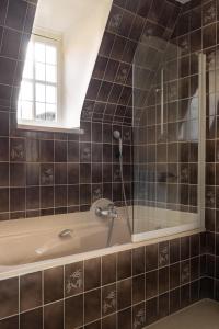 布魯日的住宿－勃艮第公爵奧克斯酒店，一间带浴缸和淋浴的浴室以及窗户。