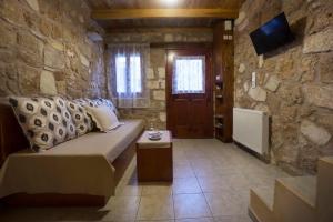 een woonkamer met een bank en een stenen muur bij Dimitra's House in Old Town in Chania