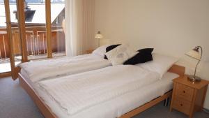 a bed with white sheets and black pillows on it at Chalet Bella Vista 3 in Wengen