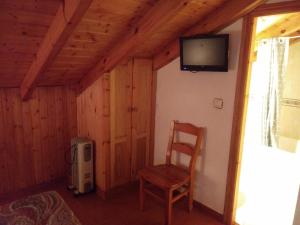 a room with a chair and a tv on a wall at Casa de Aldea La Ablanera in Cangas de Onís