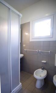 een badkamer met toilet, wastafel en raam bij Angela in Bibione