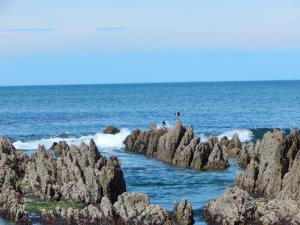 un grupo de personas con rocas en el océano en Sotavento Apart Hotel en La Paloma