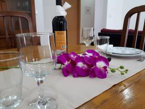 マリーニャ・グランデにあるCasa do Centroのワイングラスと紫の花が飾られたテーブル