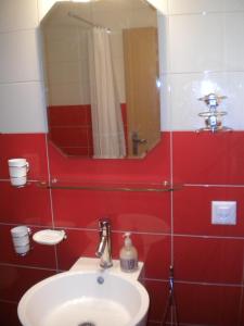 Baño rojo con lavabo y espejo en BNB Les Prises, en Les Ponts-de-Martel