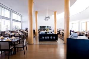 a restaurant with tables and chairs in a room with large windows at TRYP by Wyndham Porto Expo Hotel in Leça da Palmeira
