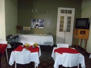 Habitación con 2 mesas con sillas blancas y TV. en Majestic Hotel, en Juiz de Fora