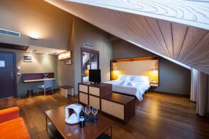 ベナスケにあるSOMMOS Hotel Anetoのベッドとテーブルが備わる広いホテルルームです。