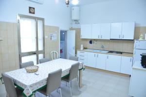 a kitchen with a table and chairs and white cabinets at Casa Vienna in Salice Salentino