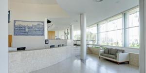 a lobby with a waiting room with a chair and windows at TRYP by Wyndham Porto Expo Hotel in Leça da Palmeira