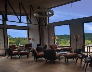 a waiting room with chairs and tables and large windows at Mantadia Lodge Andasibe in Andasibe