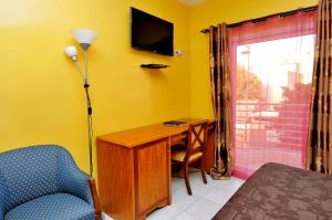 a bedroom with a desk and a chair and a television at Résidence De La Porte Du Millenaire in Dakar