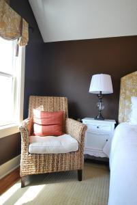 um quarto com uma cadeira, uma almofada e uma cama em The Oriole em Saugatuck