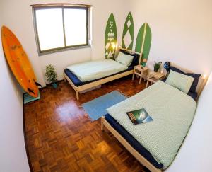 Pokój z dwoma łóżkami i deskami surfingowymi na ścianie w obiekcie My Powderwave Ericeira w mieście Ericeira