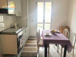 ガリポリにあるBaia Verde Appartamenti Gallipolitravelのキッチン(紫のテーブルクロス付きのテーブル付)