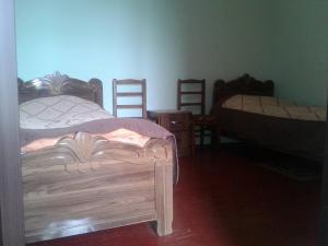 a bedroom with two beds and several wooden chairs at Mila Guest House in Mazeri