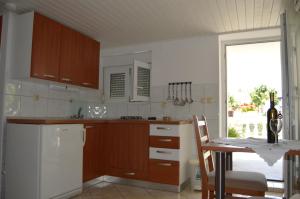 a kitchen with wooden cabinets and a table and a window at Apartman Latin 1 in Vodice