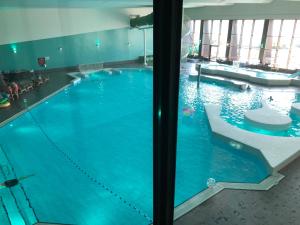 a large swimming pool with blue water in a building at Ferienhaus Ooghduyne 176 in Julianadorp