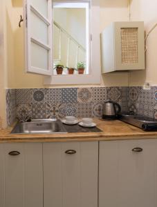 a kitchen with white cabinets and a sink at Antica Casa Studios in Chania