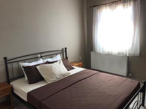 una camera da letto con letto, cuscini e finestra di Livadi center mountain view apartment a Livadi