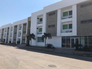 a large white building with palm trees in front of it at Hotel Via 40 in Barranquilla