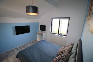 a bedroom with a bed and a tv and a window at Ferienhaus Ooghduyne 176 in Julianadorp +36 photos