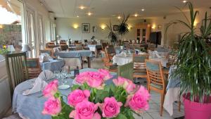 un restaurante con mesas con rosas rosas. en Hôtel Restaurant Alios en Bas-Mauco