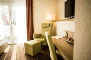 a hotel room with a desk and a chair and a table at Landgasthof "Zum grünen Walde" in Nordholz