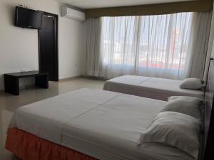 Habitación de hotel con 2 camas y TV de pantalla plana. en Hotel Via 40, en Barranquilla