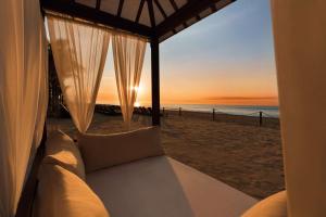 a couch sitting on the beach with the sunset at Hyatt Ziva Los Cabos - All Inclusive in San José del Cabo