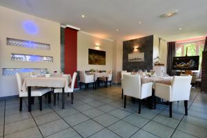 una sala da pranzo con tavoli e sedie bianche di Logis Hôtel Restaurant Le Castel Fleuri a Saint-Jean-en-Royans