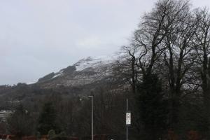 a snow covered mountain with trees and a street sign at Stroma in Portree