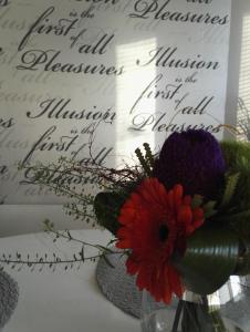 a vase with flowers on a table with writing on the wall at Peaceful City Centre Apartment (2 Bdr) in Rovaniemi