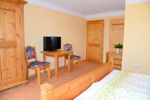 Schlafzimmer mit einem Bett und einem Schreibtisch mit einem TV in der Unterkunft Gästehaus zum Prinzenfelsen in Nagel