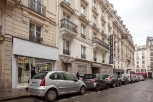 eine Reihe von Autos, die auf einer Straße neben Gebäuden geparkt sind in der Unterkunft Hotel d'Amiens in Paris